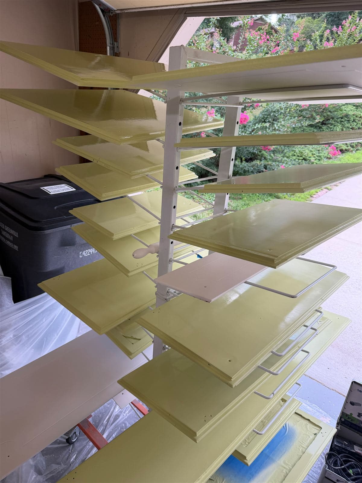 Cabinet doors drying on racks after being sprayed in a soft green