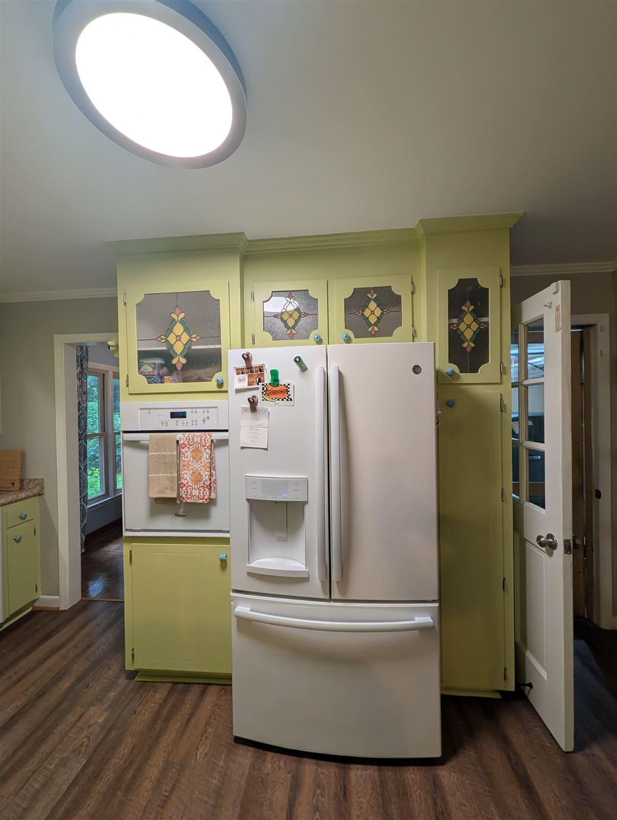 Oven and refrigerator wall with cabinets repainted in soft green in Taylors, SC