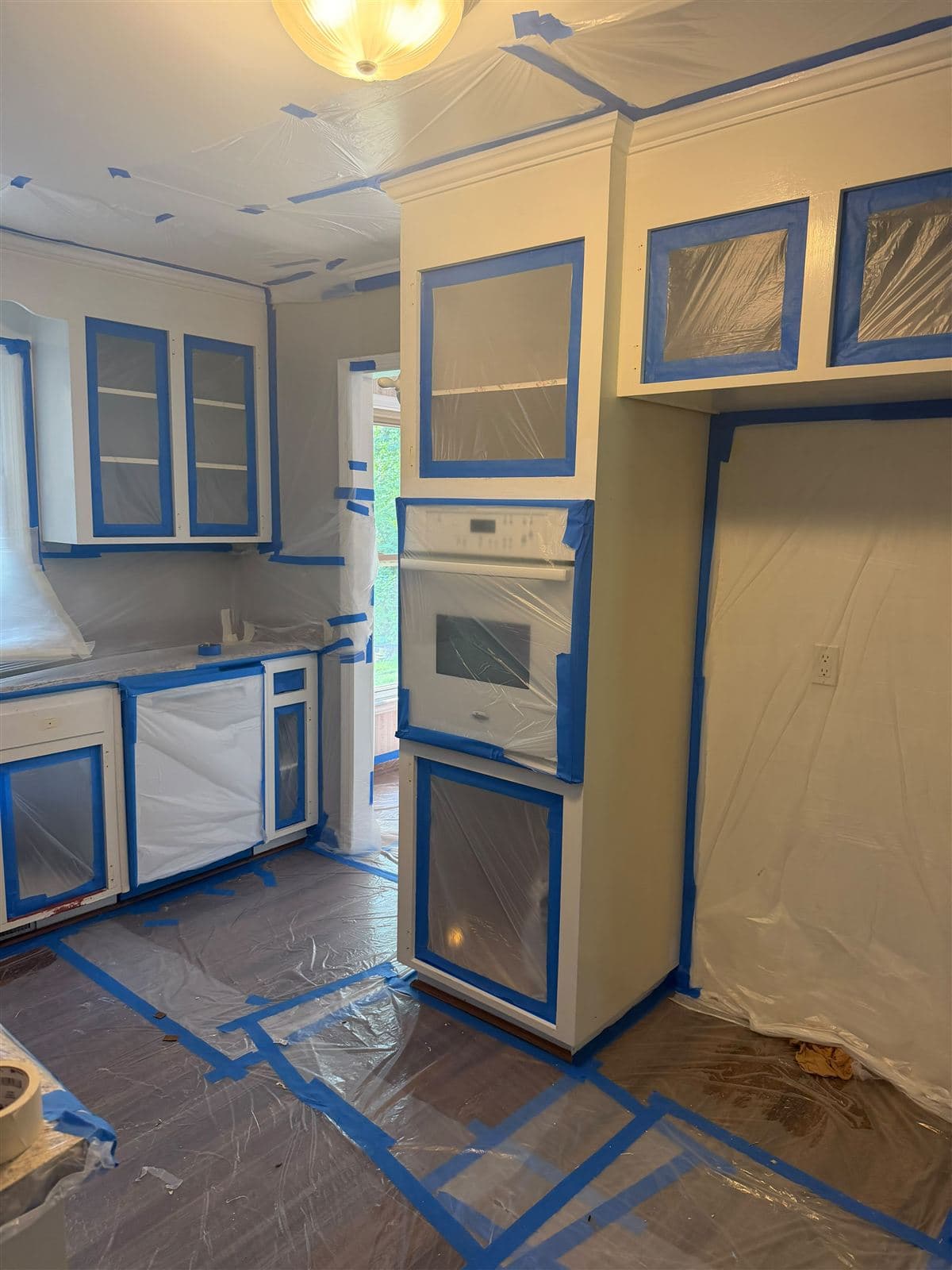 Wall oven and pantry wall sealed in plastic during cabinet painting in Taylors, SC