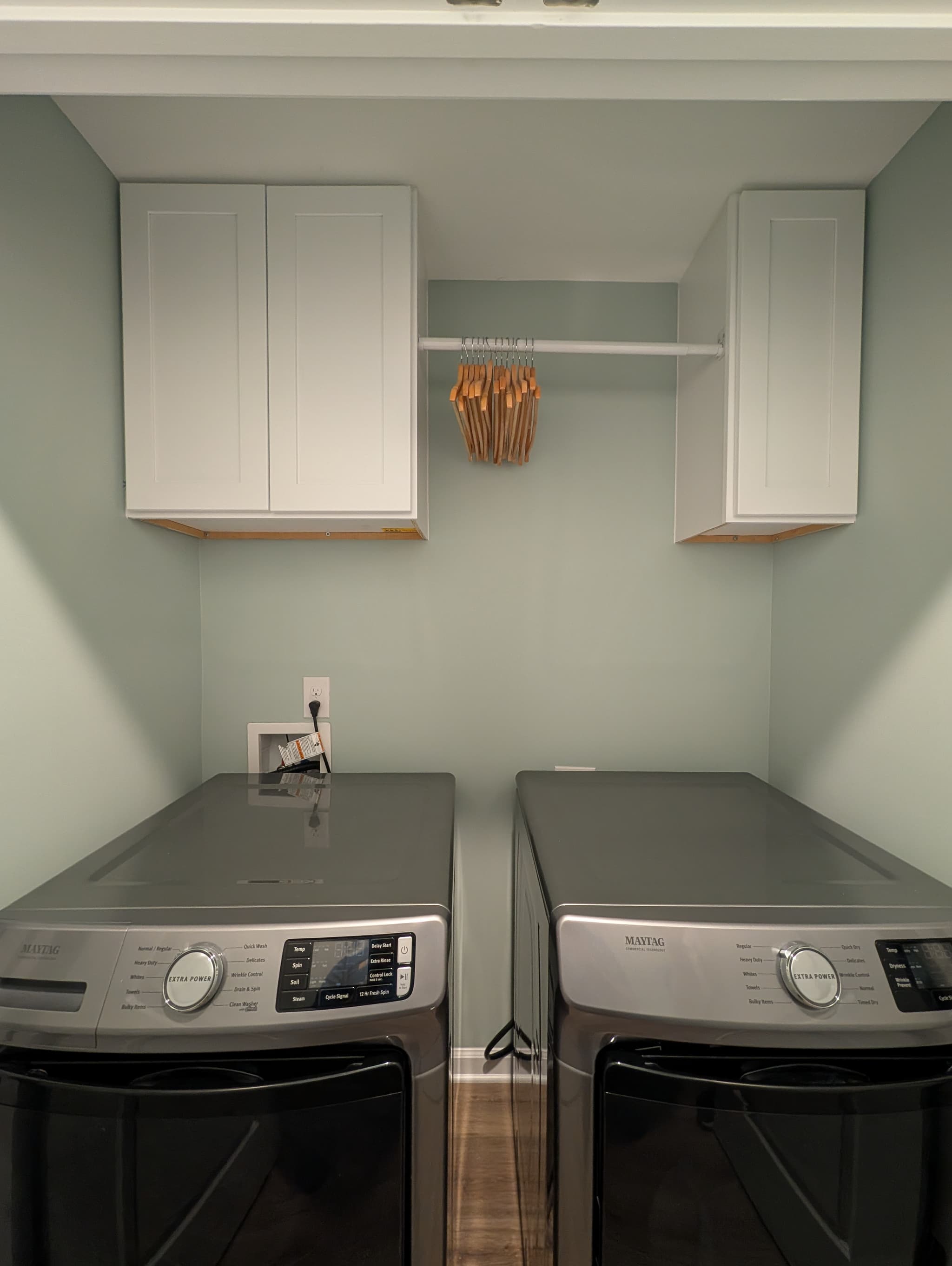 White cabinets and a hang-dry rod installed in a Simpsonville laundry closet