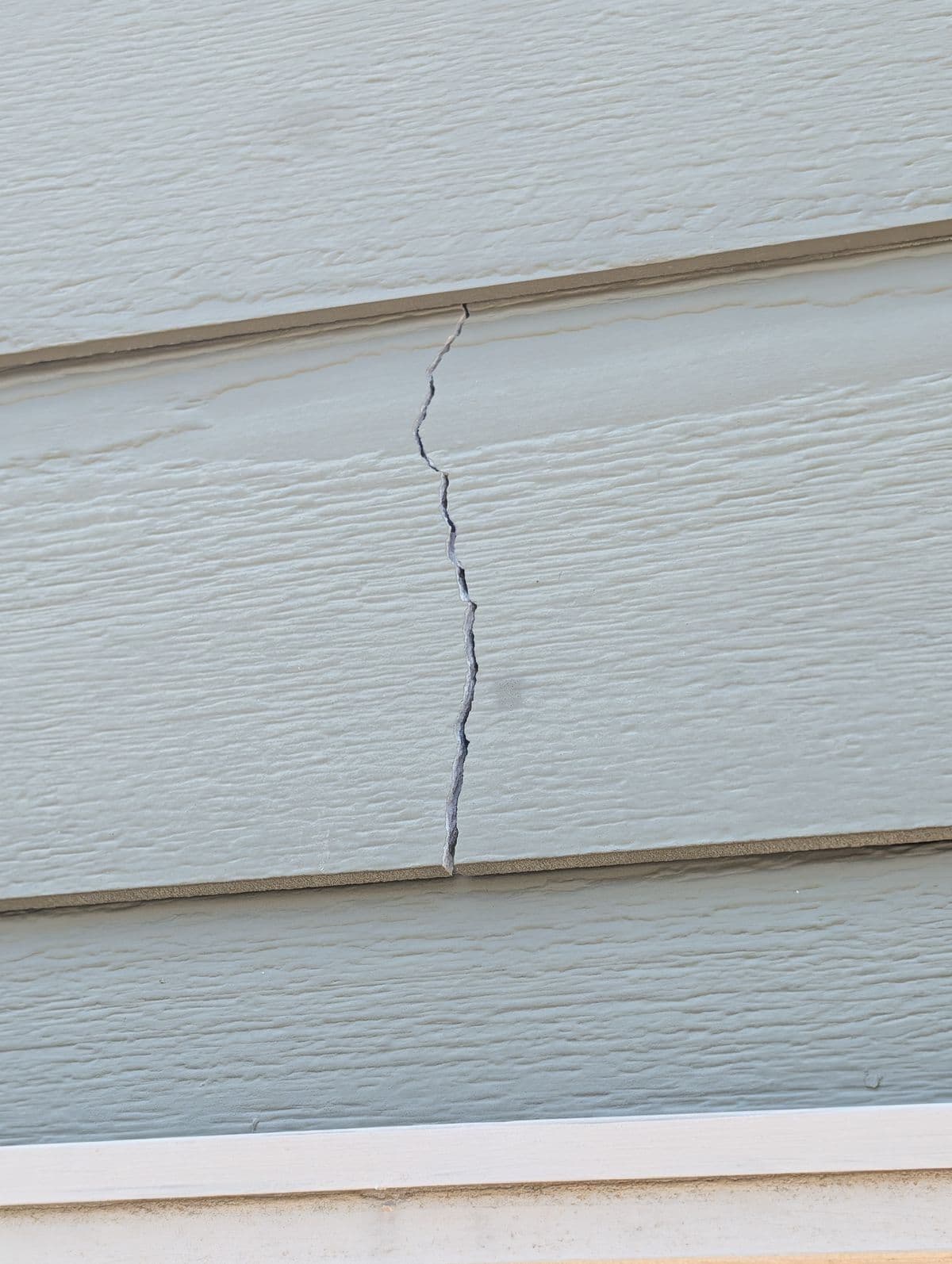 Crack running vertically through fiber-cement lap siding before repair in Simpsonville, SC