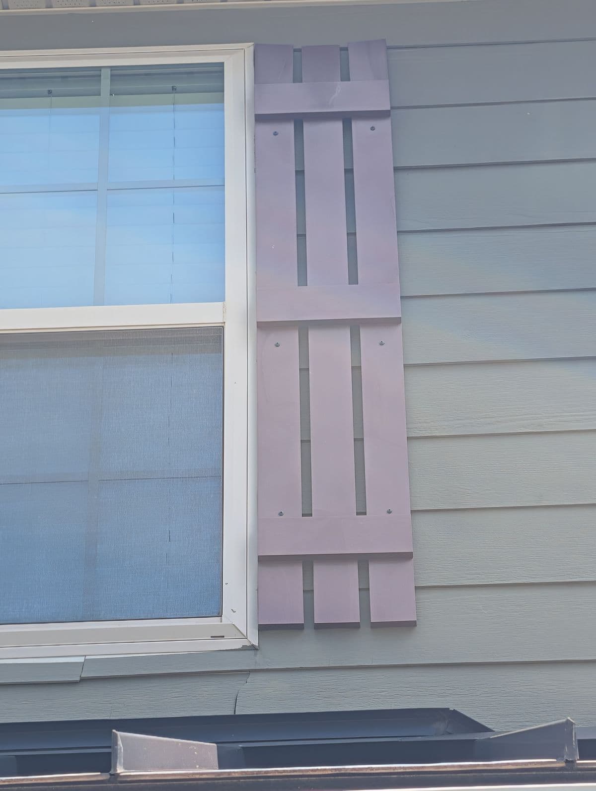 Sun-faded, chalky shutter beside a window before repainting