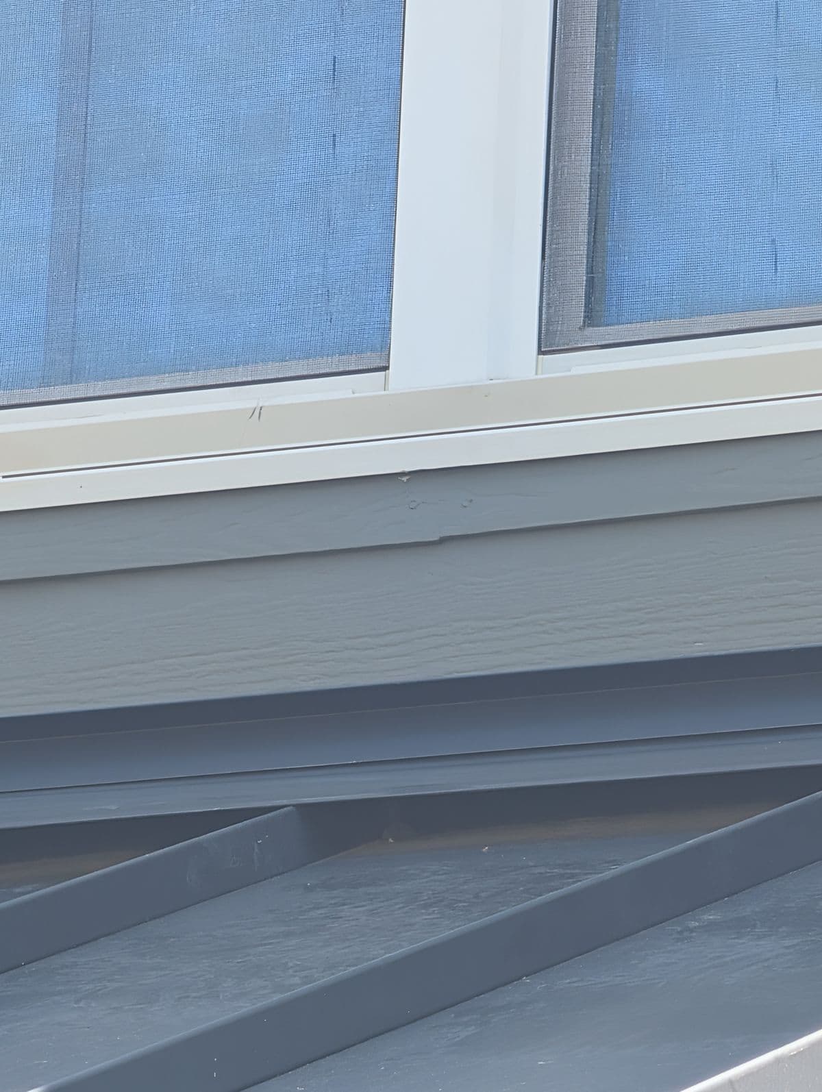 Repaired siding and repainted trim beneath the same window after the project