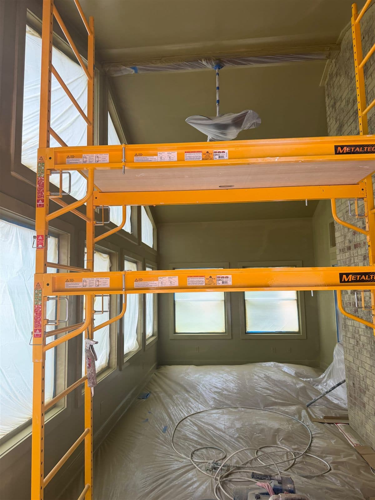 Lake room masked for spraying with scaffolding, covered floors, and the green going on in Pelzer, SC