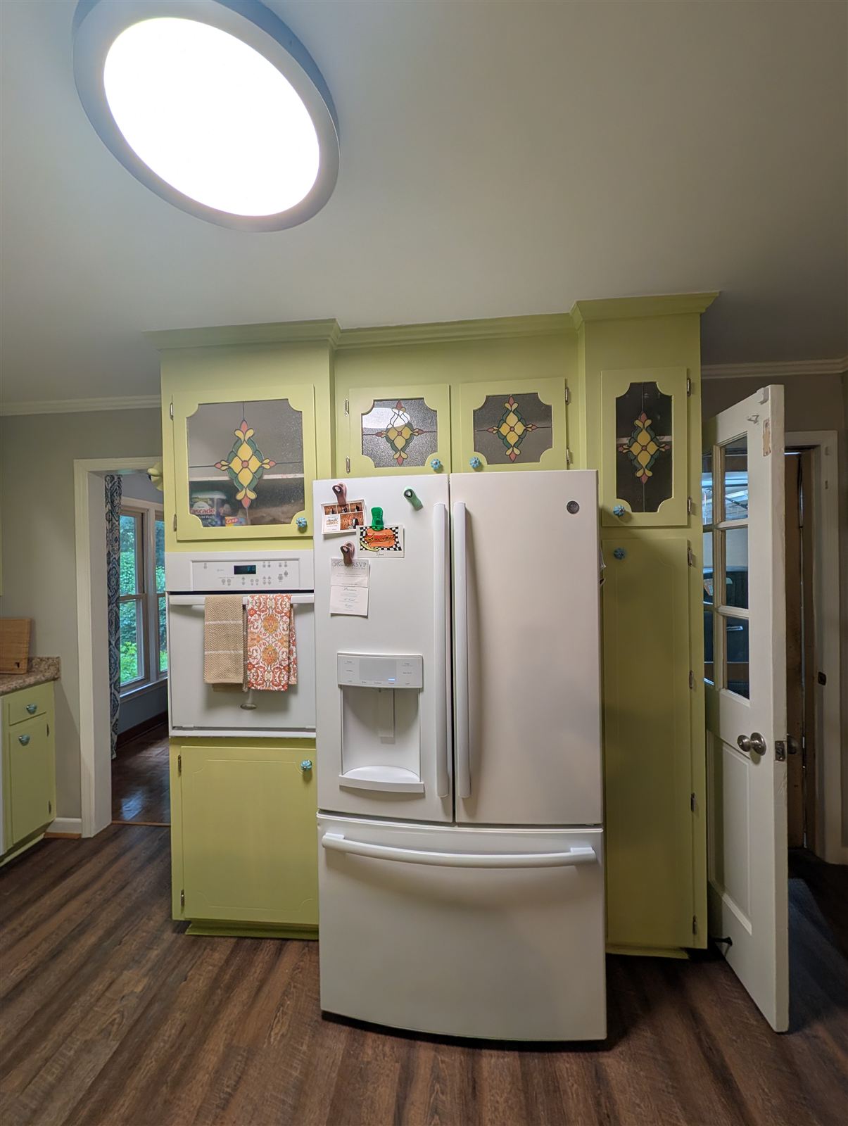 Oven and refrigerator wall with cabinets repainted in soft green in Taylors, SC
