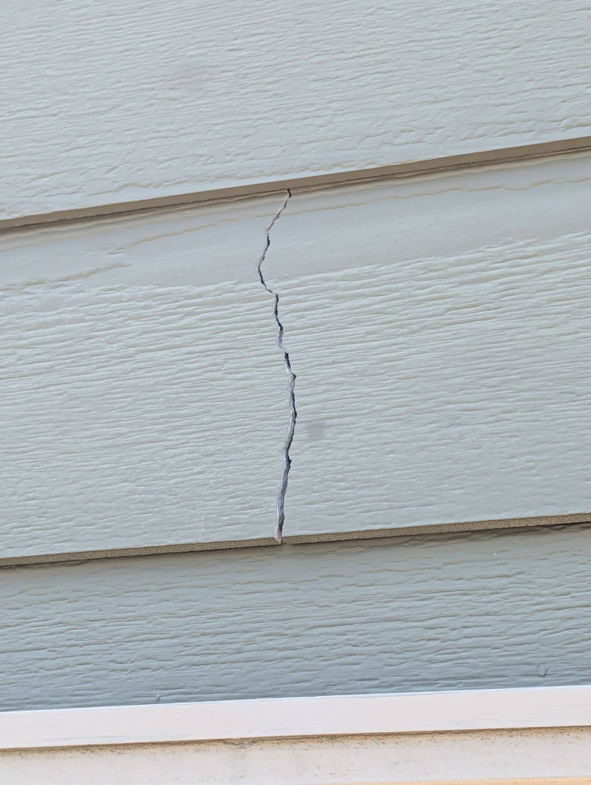Crack running vertically through fiber-cement lap siding before repair in Simpsonville, SC