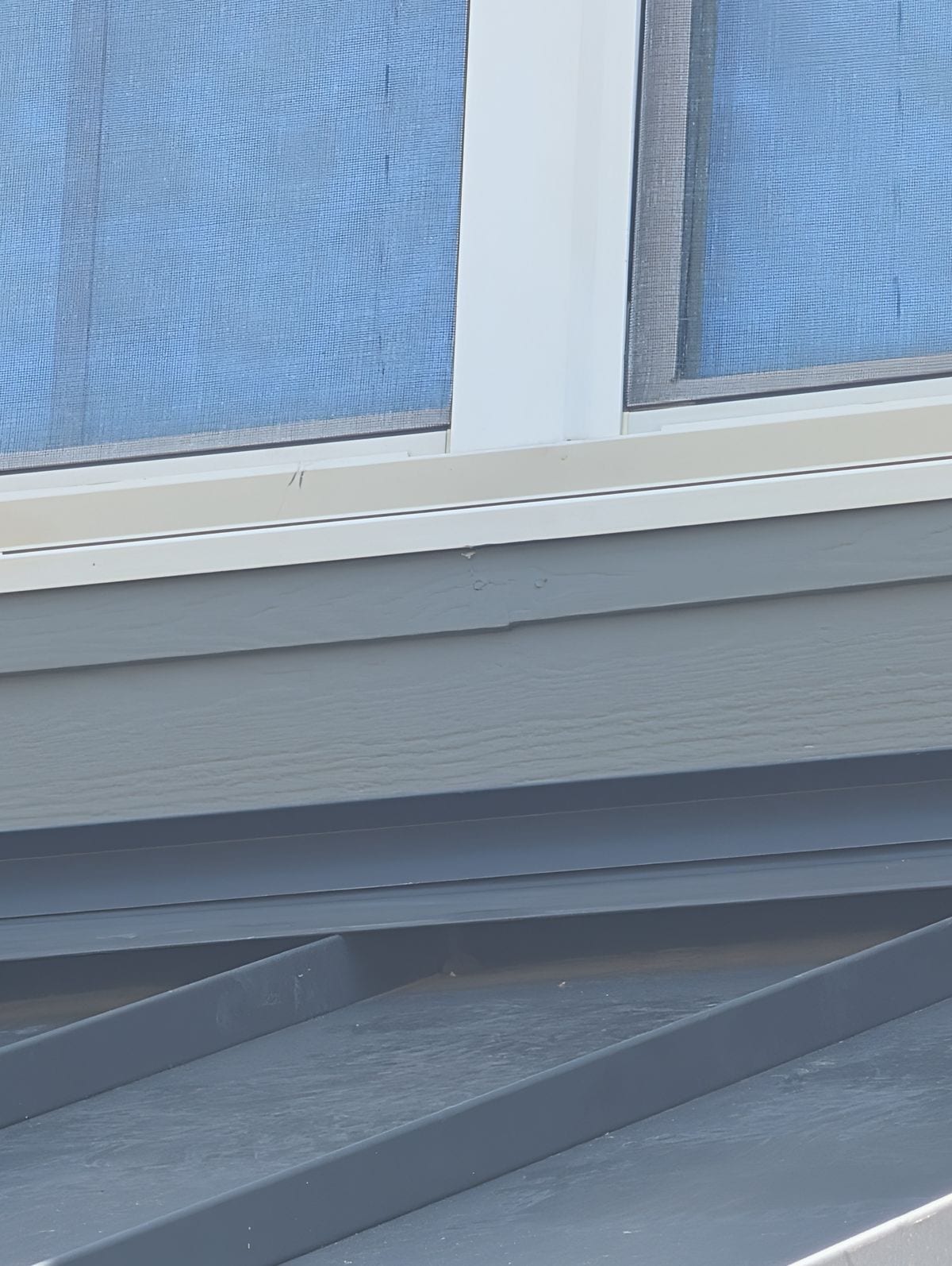 Repaired siding and repainted trim beneath the same window after the project